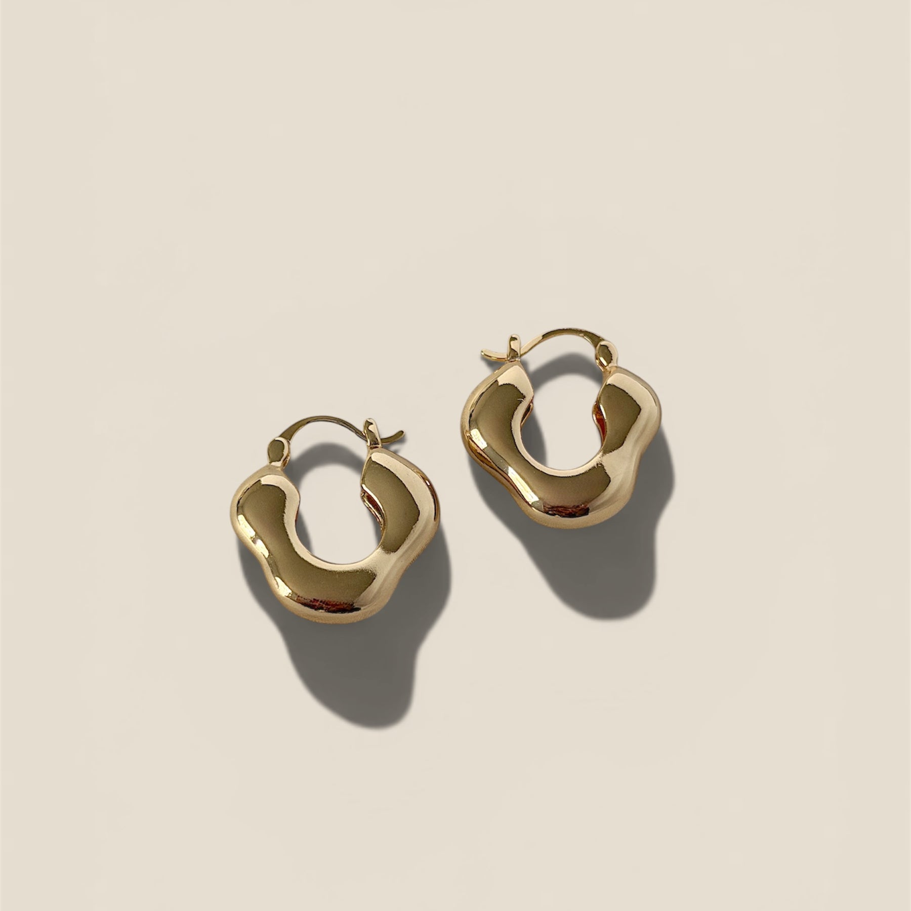 Gold hoop earrings on a beige background