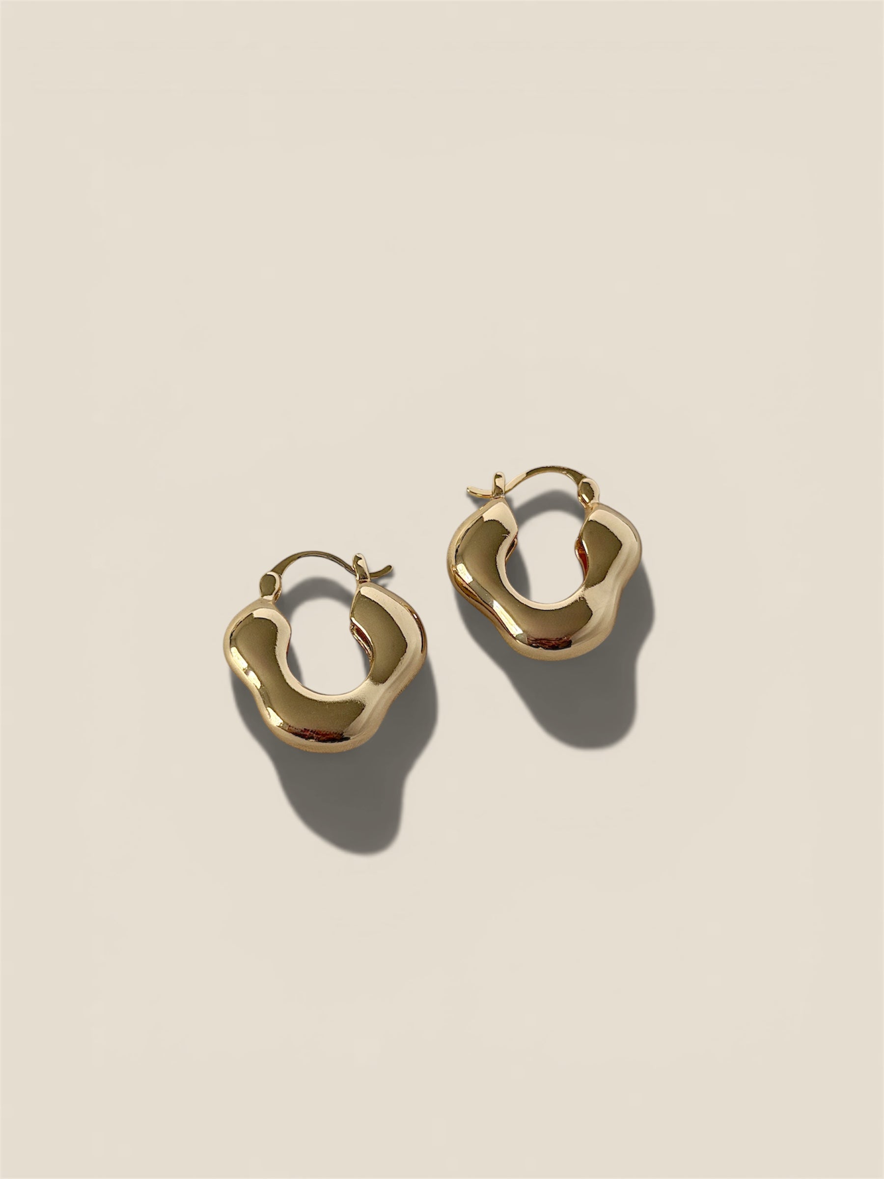 Gold hoop earrings on a beige background