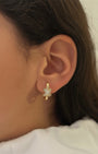 Close-up of a person wearing a gold earring with a diamond-like stone.