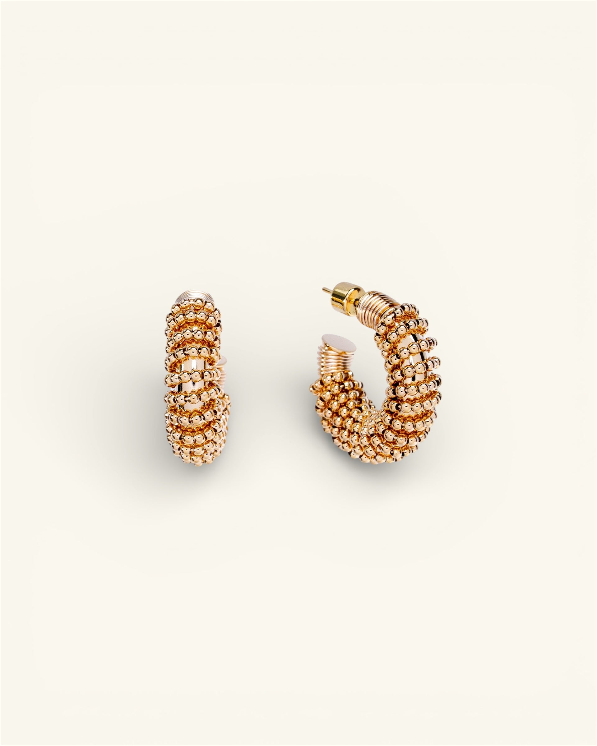 Pair of gold hoop earrings on a light beige background